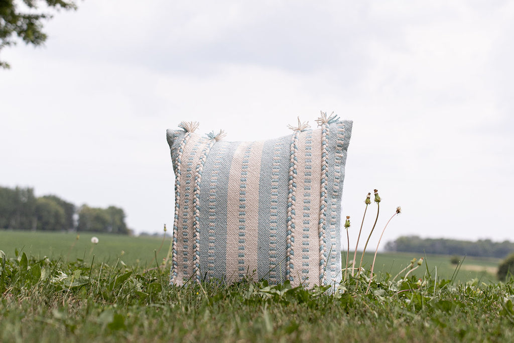 light blue and white woven outdoor pillow on hillside