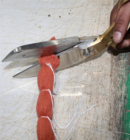 scissor cutting tied yarns to make pom poms