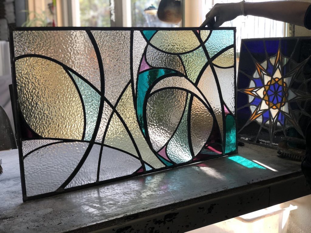 Swirling stained glass panel held in place on a work bench. Final presentation of stained glass.