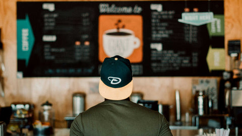 man standing looking at coffee shop menu