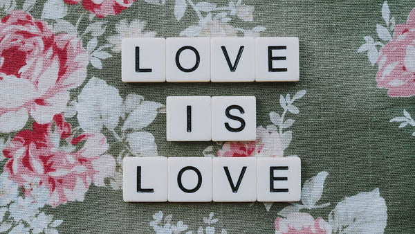 A Love is Love Slogan Spelled with White Letter Blocks on a Floral Textile