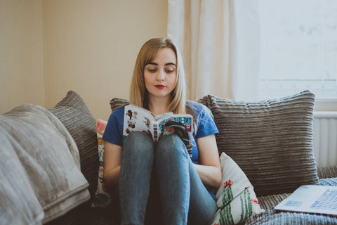 Woman Sitting On Couch While Reading A Manga Book