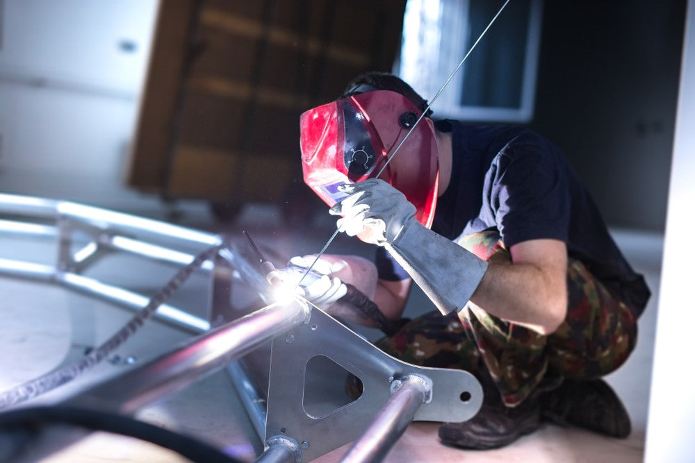 Man welding aluminum truss with welding rod