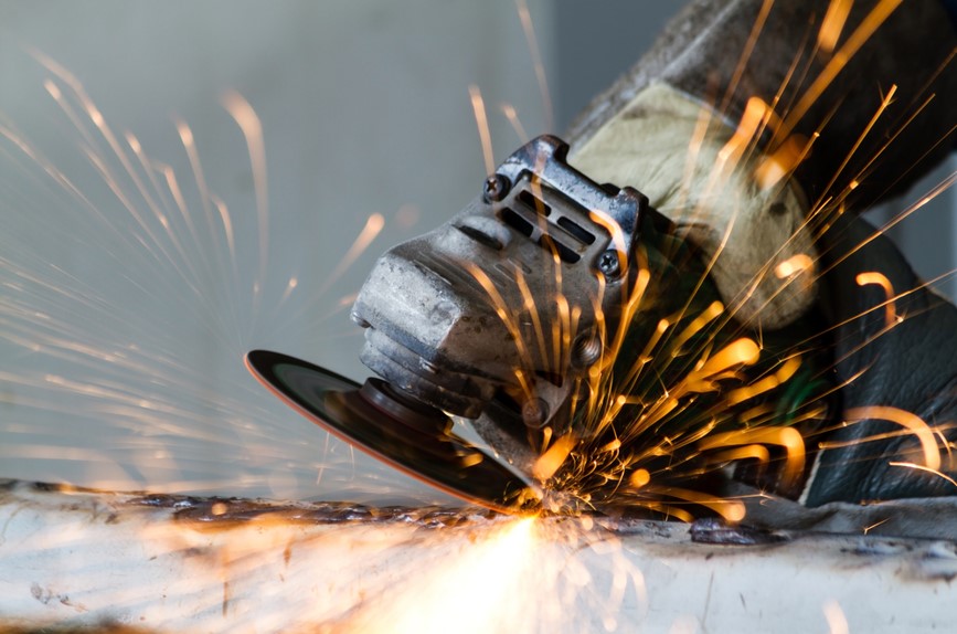 Metal grinding wheel on grinder cutting through steel pipe with sparks
