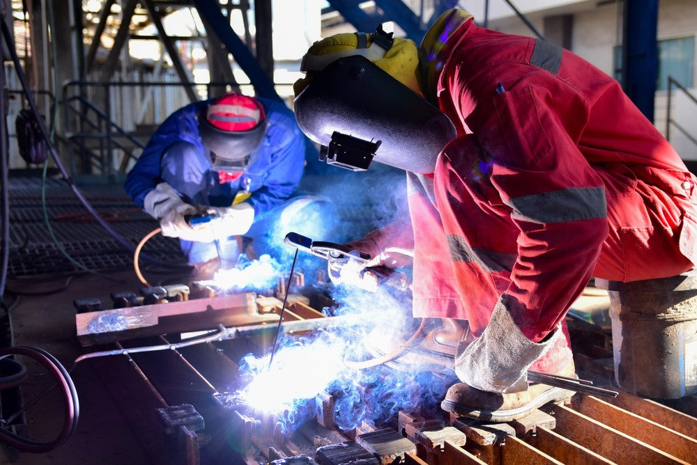 Two welders working together to assemble workpiece