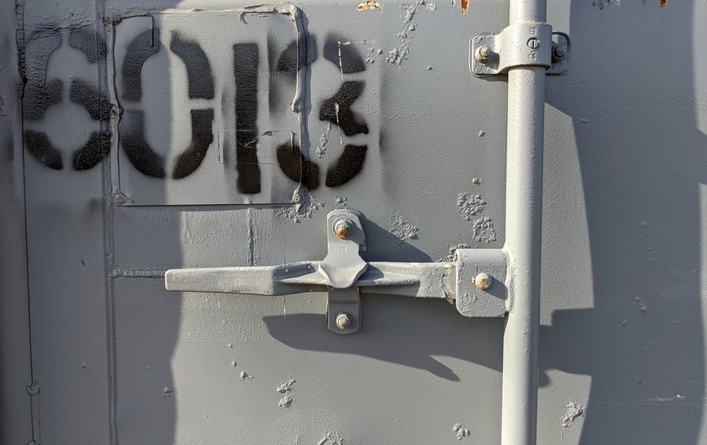 Welded latch on door of shipping container