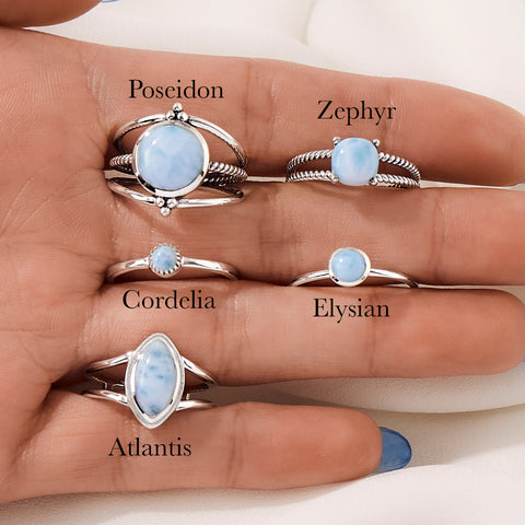 Image of 5 sterling silver Larimar stone rings placed in between fingers