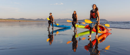 3 people with kayaks on the beach