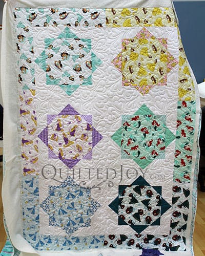 Colleen shows off her Disney Princesses Quilt after renting a longarm machine at Quilted Joy