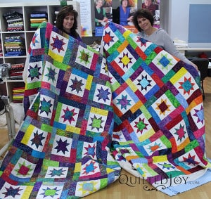 Paula and Lark showoff their Sawtooth quilts after their longarm quilting machine rental at the Quilted Joy showroom.