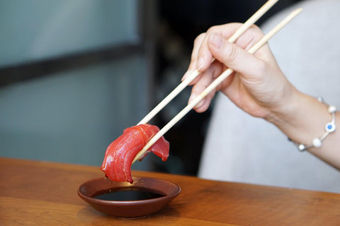 dipping a piece of nigiri sushi into tamari