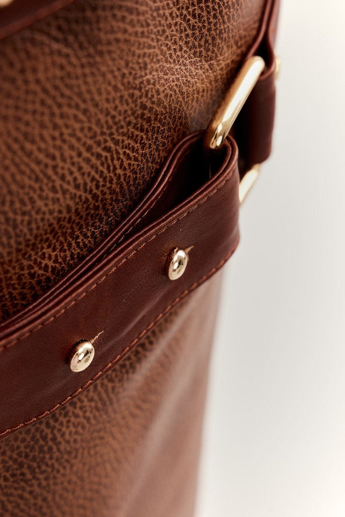 Zoom on a luxury cognac color texturized leather apron with gold hardware and chicago screws