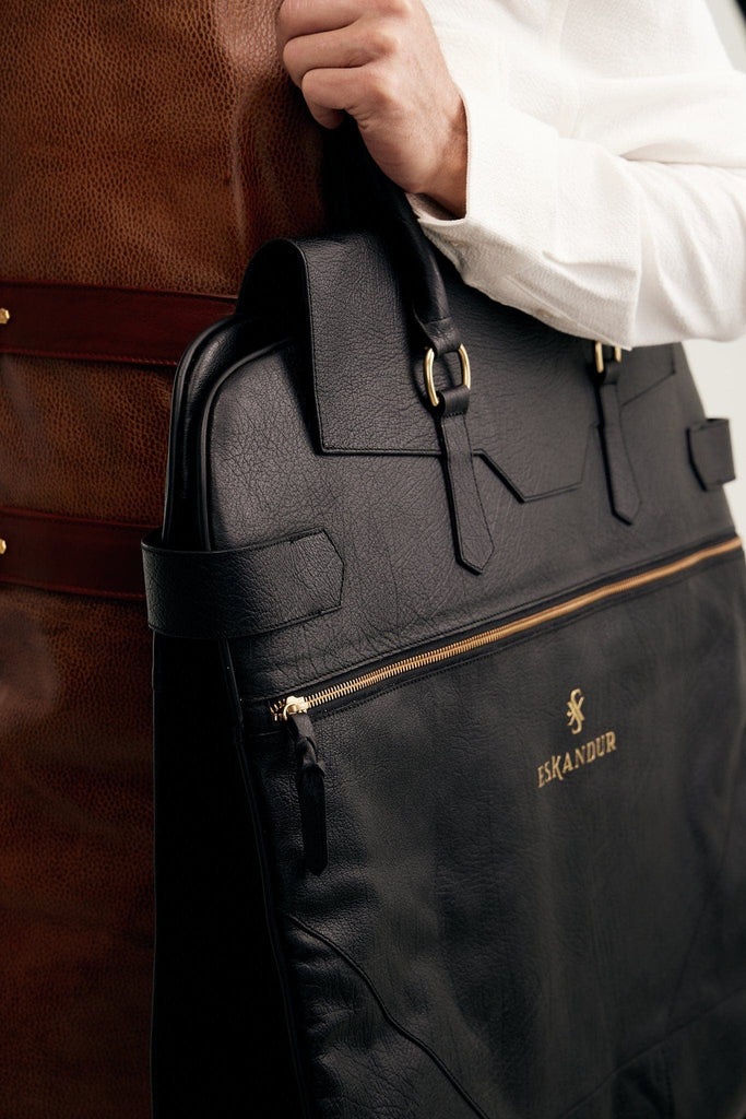 Man wearing a Luxury leather black garment bag with the handles on his elbow.