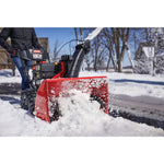 CRAFTSMAN Electric Start Two-Stage Snow Blower in front view blowing snow in driveway wearing black jacket 
