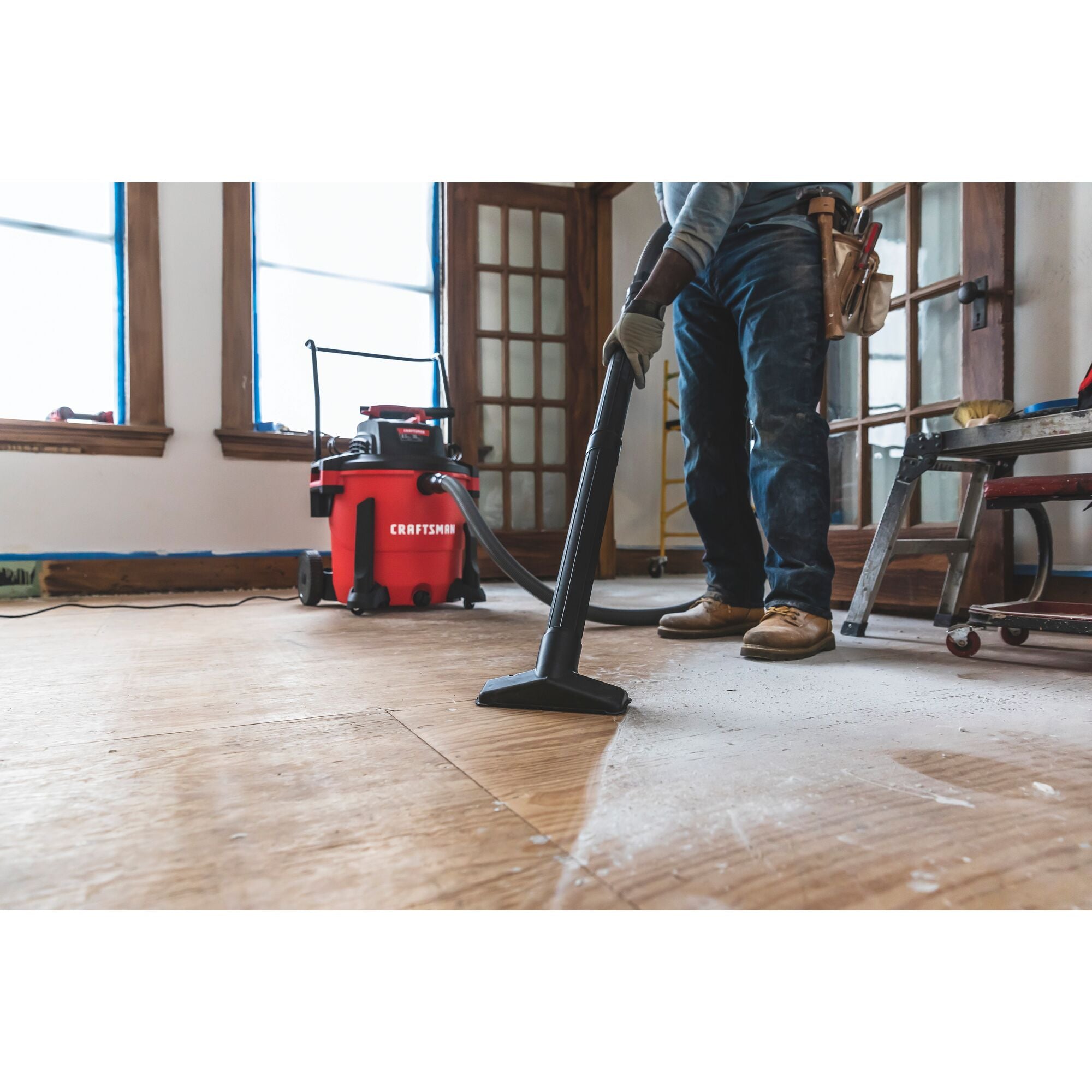 20 gallon 6.5 H P wet dry vacuum with cart being used by a person to clean wooden floor.