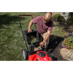 CRAFTSMAN 140cc Push Mower in top view being emptied with maroon shirt 