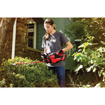 Cordless 22 inch hedge trimmer being used to trim bushes.