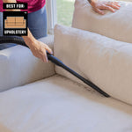 Homeowner using long flexible crevice tool accessory with wet dry shop vacuum to clean sofa in home