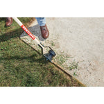 Wood handle edger being used to make a clean edge against the pavement.