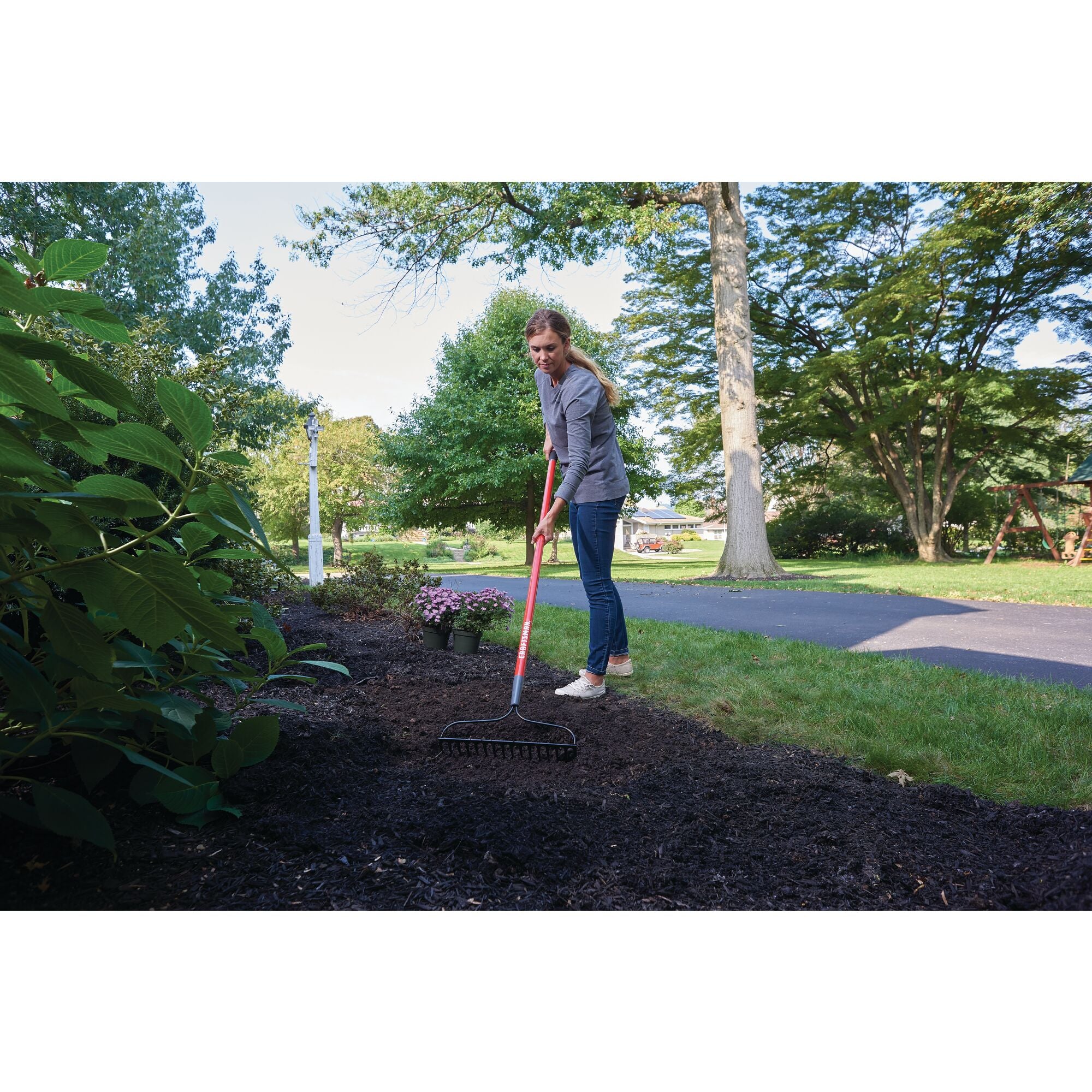 Fiberglass handle garden rake being used by a person.