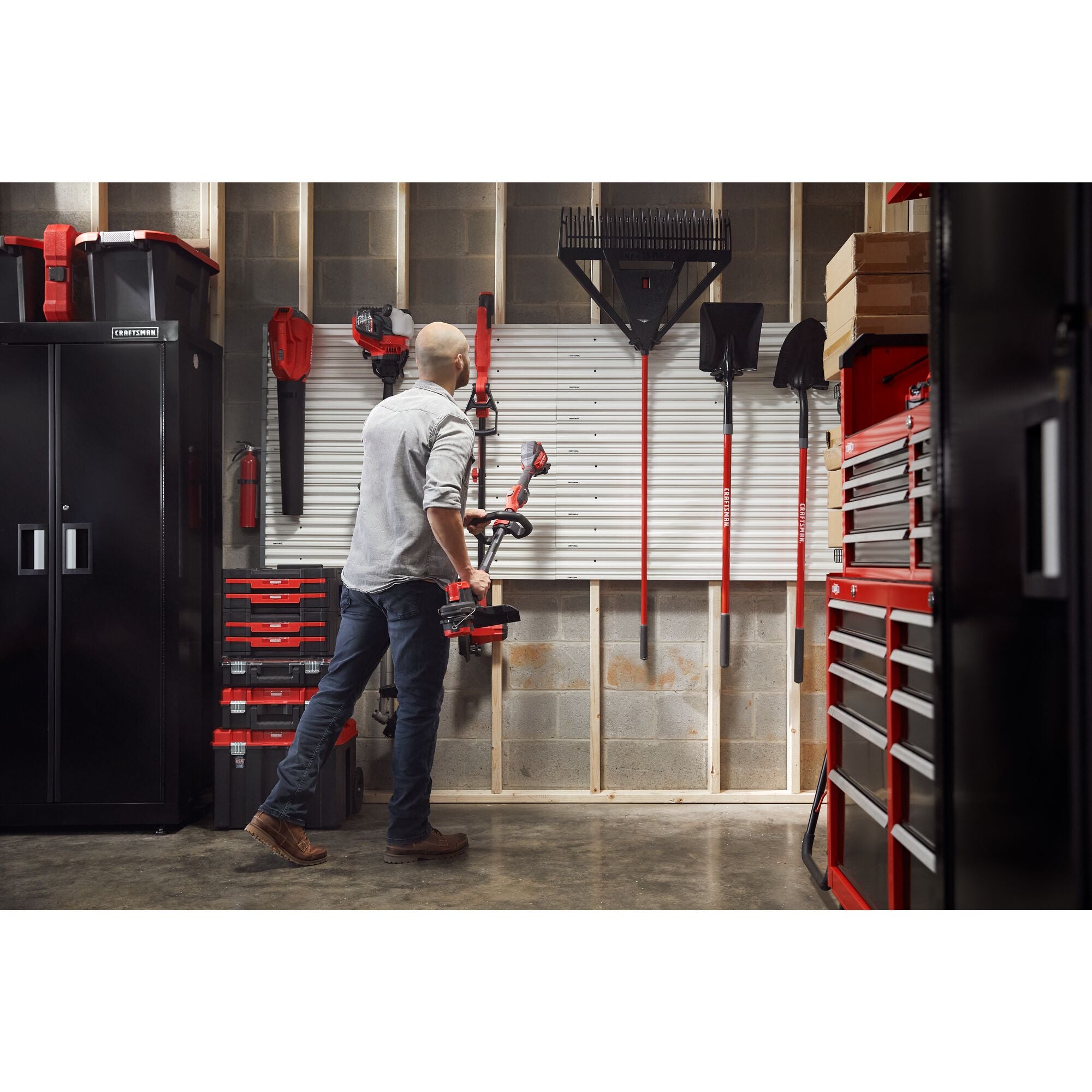 Man handing trimmer on versatrack with garage filled with power tools, storage, outdoor products