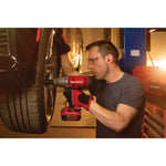 Cordless half inch impact wrench kit 1 battery being used to tighten tyre screws by person.