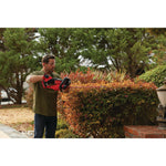 Cordless 22 inch hedge trimmer being used to level hedge.