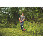 60 volt cordless 15 inch brushless weedwacker string trimmer with quickwind kit 2.5 ampere per hour being used by a person to cut overgrown weeds outside.