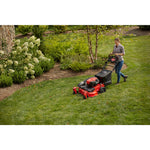 CRAFTSMAN M430 28-In. 223cc Rwd Self-Propelled Mower mowing near flowerbed with jeans and plaid shirt