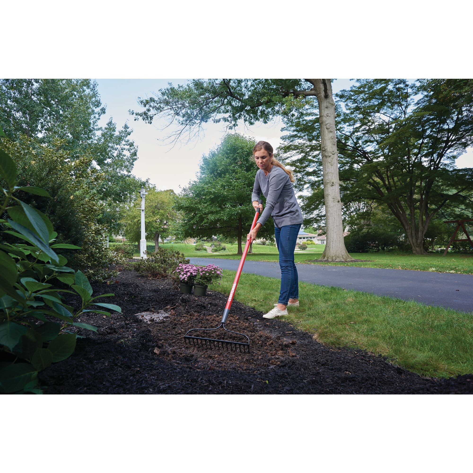 Fiberglass handle garden rake being used by a person.