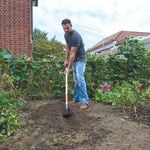 Wood handle planting hoe being used by a person.