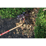 11 tine wood handle shrub rake being used to rake leaves from the ground.