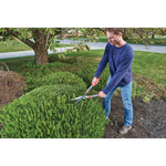 Multi purpose hedge shears being used by a person to trim a hedge.