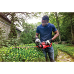 Cordless 22 inch hedge trimmer being used to level hedge by person.