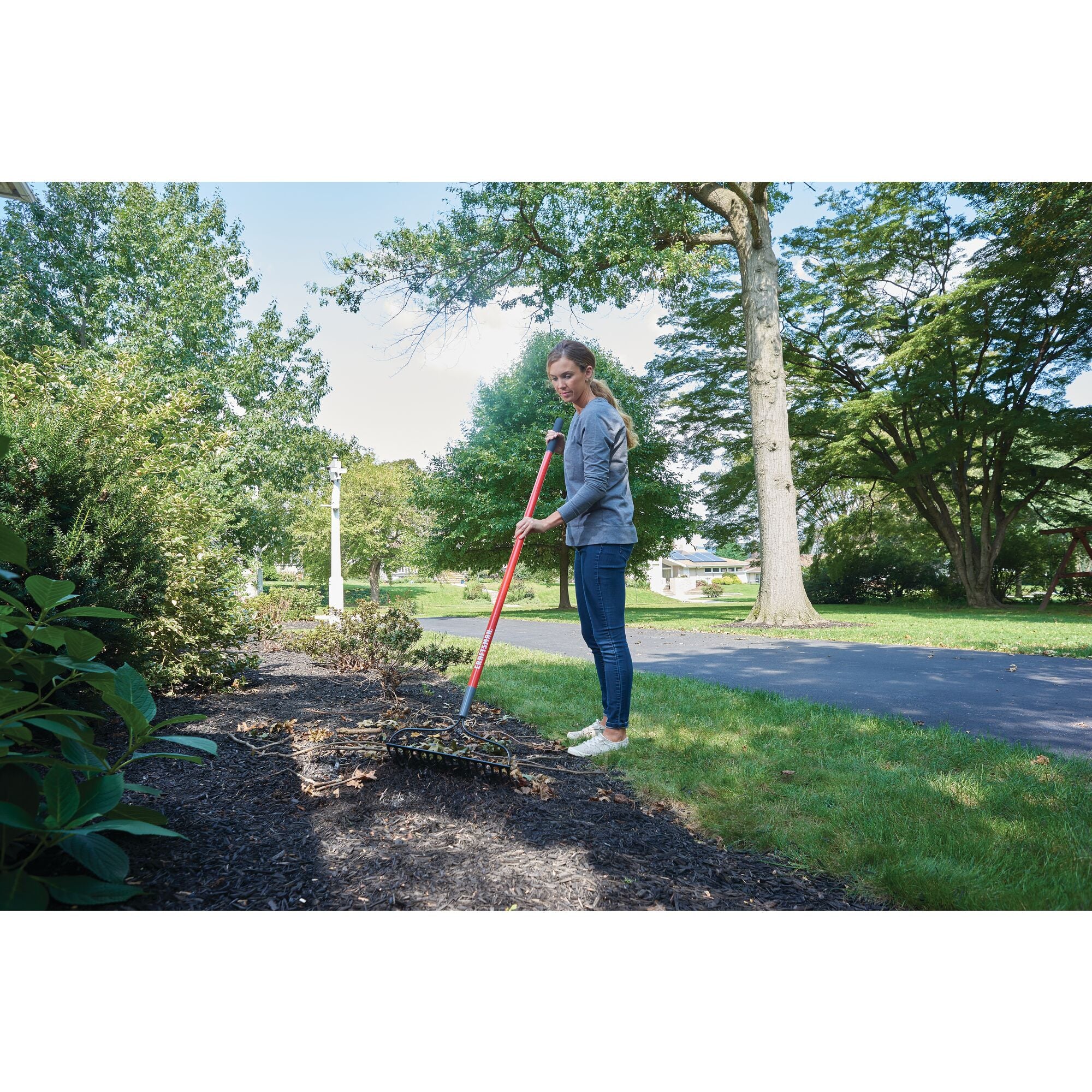 Fiberglass handle garden rake being used by a person.