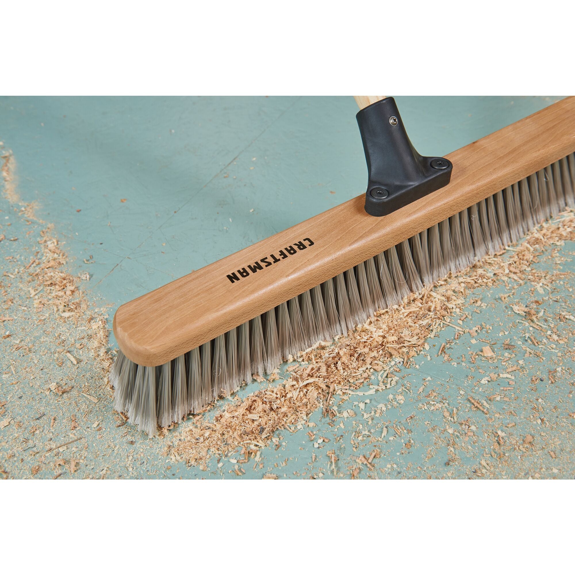 24 inch shop-and-garage push broom head close up cleaning sawdust on vinyl floor