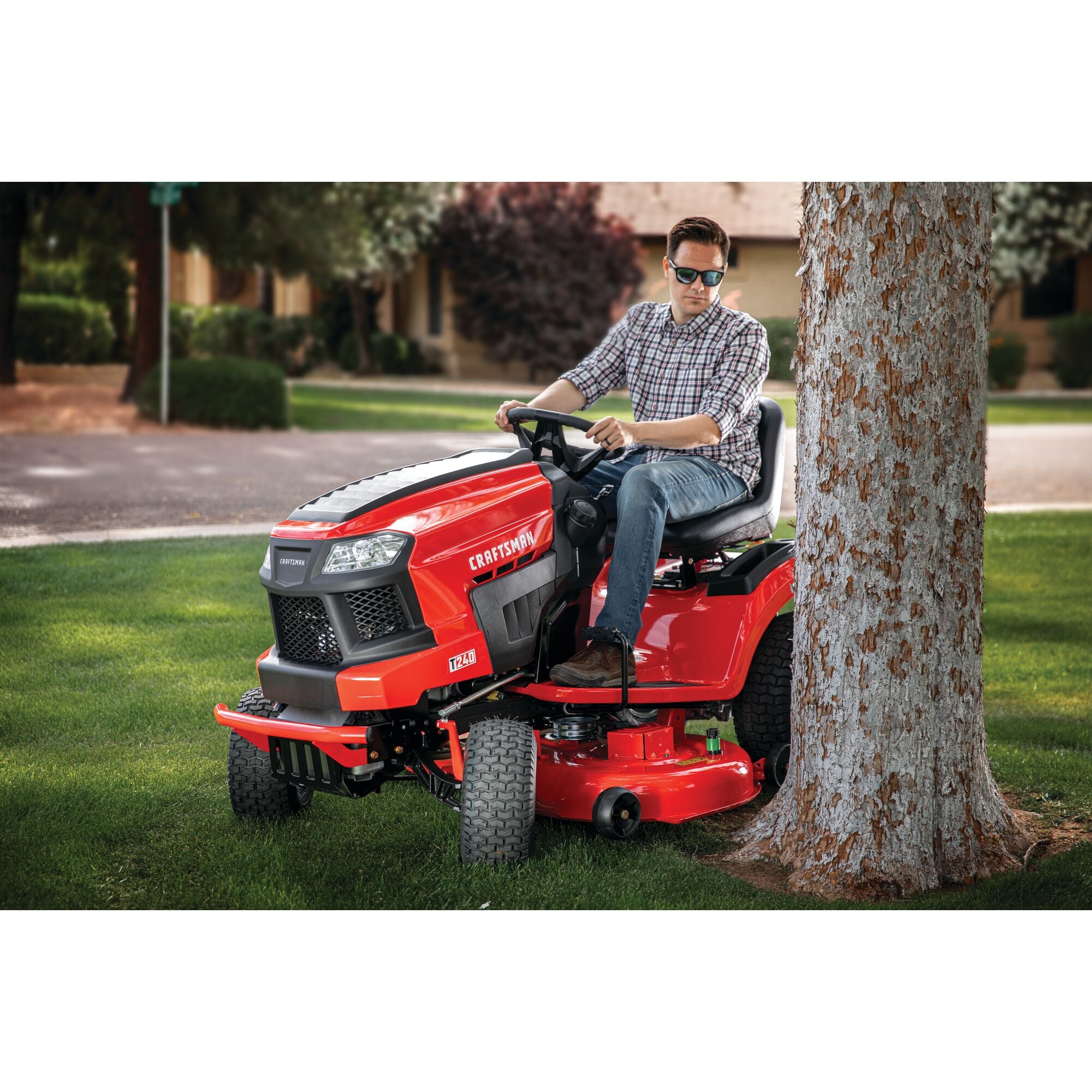 46 inch 22 h p hydrostatic riding mower with turn tight being used by a person to mow the lawn beside a tree.