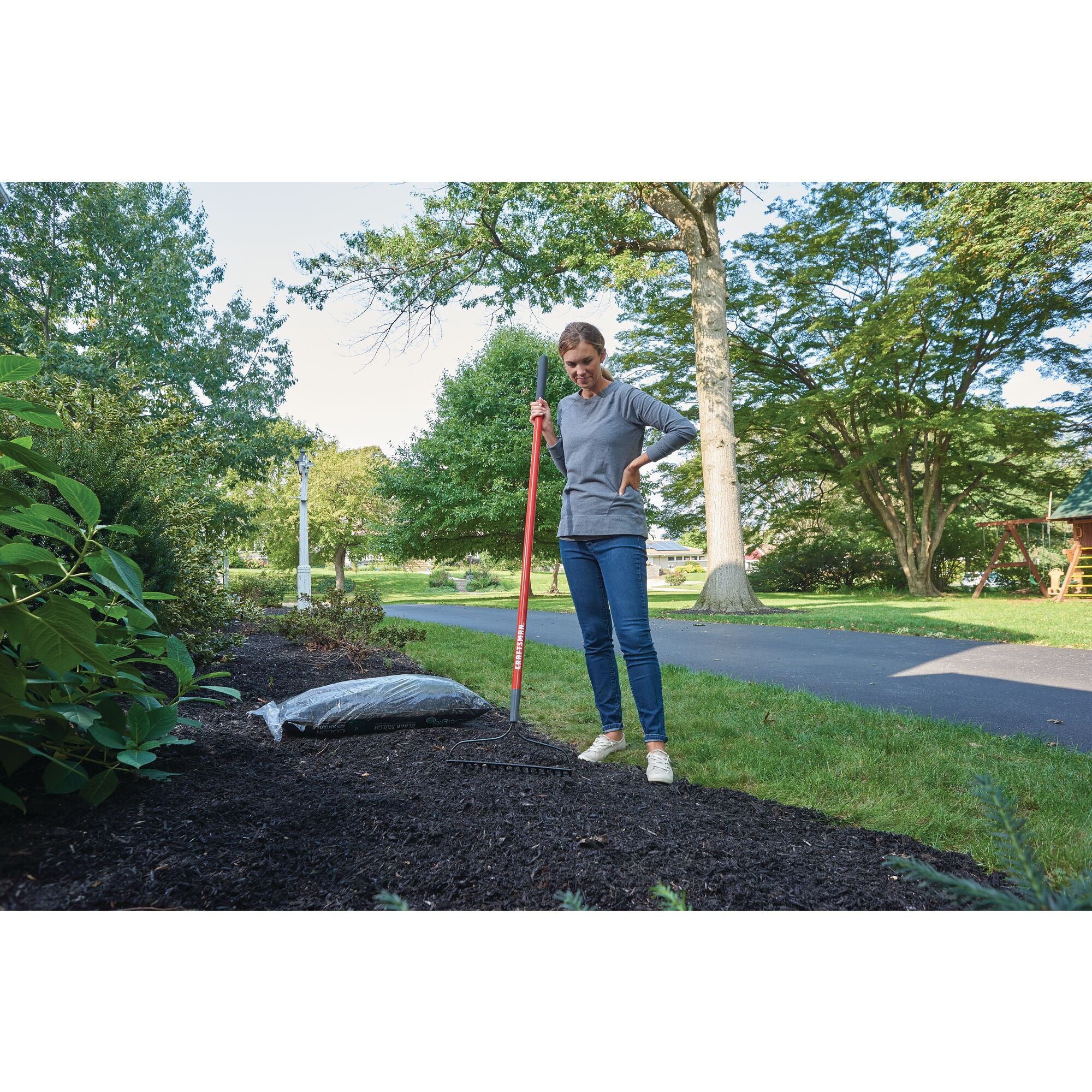 Fiberglass handle garden rake being used on a side walk.