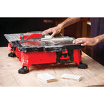 20 volt 7 inch cordless compact wet tile saw being used by a person to cut a tile.