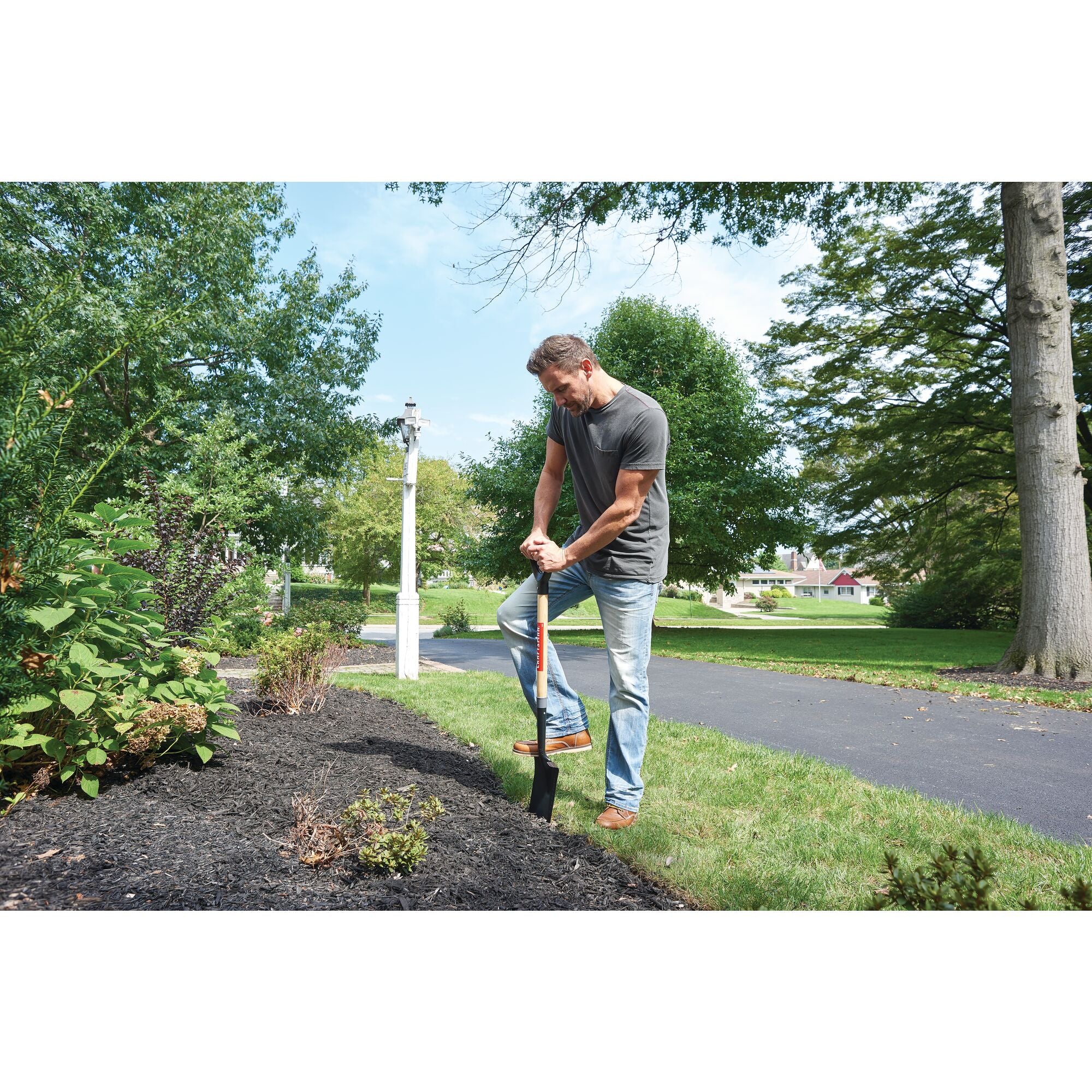 Wood handle border spade being used to dig up dirt by a person.