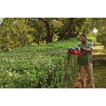 Cordless 24 inch hedge trimmer kit 2.5 Ampere hours being used to level hedge top.