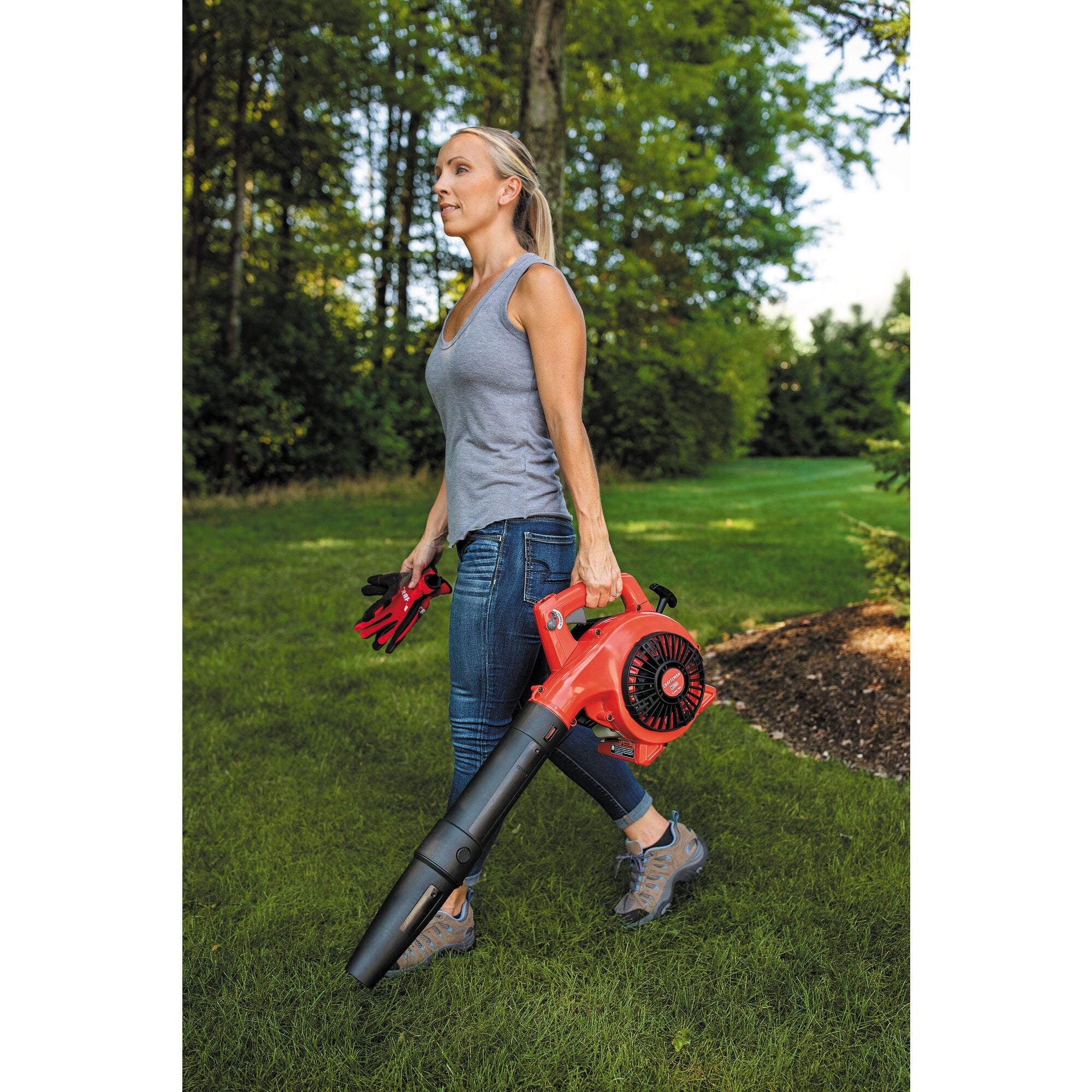 25 C C 2 cycle gas leaf blower being carried by a person outdoors.