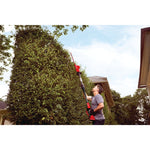 20 volt 18 inch cordless pole hedge trimmer kit being used by a person to trim plants outdoors.