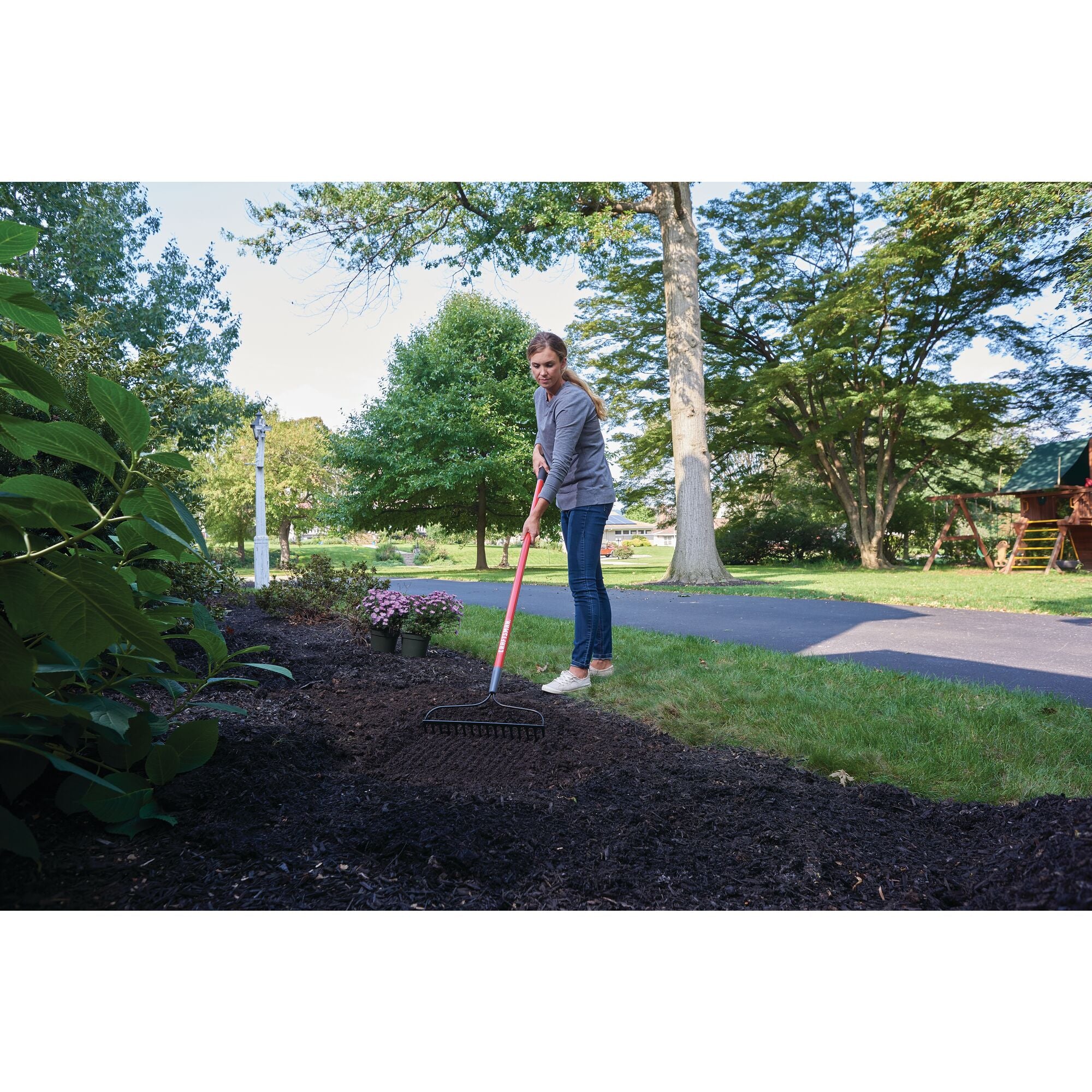 Fiberglass handle garden rake being used by a person.