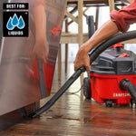Homeowner using flexible crevice tool with CRAFTSMAN 4 gallon vacuum to cleanup water in kitchen