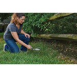 Swivel grass shears being used by a person to trim grass outdoors.