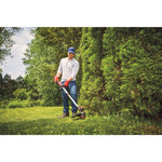 20 volt weedwacker 13 inch cordless string trimmer and edger with push button feed kit being used by a person to cut outgrown weeds.