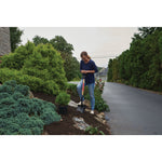 Wood handle digging shovel being used by a person to shovel dirt from a sidewalk garden.