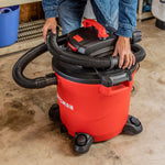 Top view of person wrapping cord around top handle of CRAFTSMAN wet dry shop vacuum with hose stored