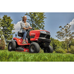 Riding mower with mulching kit being used by a person to mulch grass.